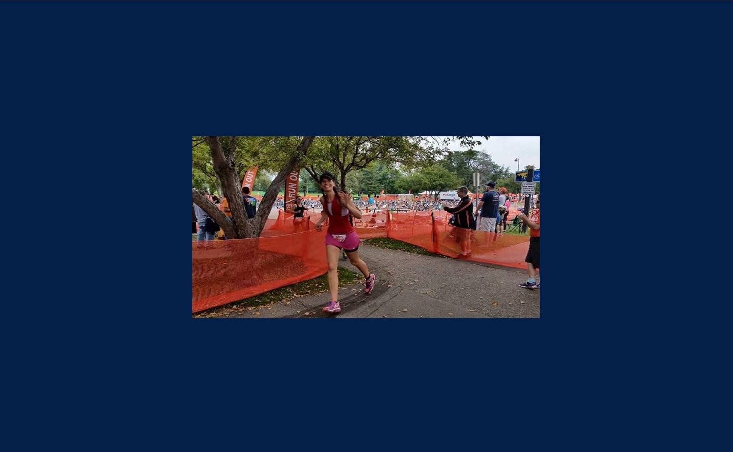 Amy running by an orange fence along the triathalon route