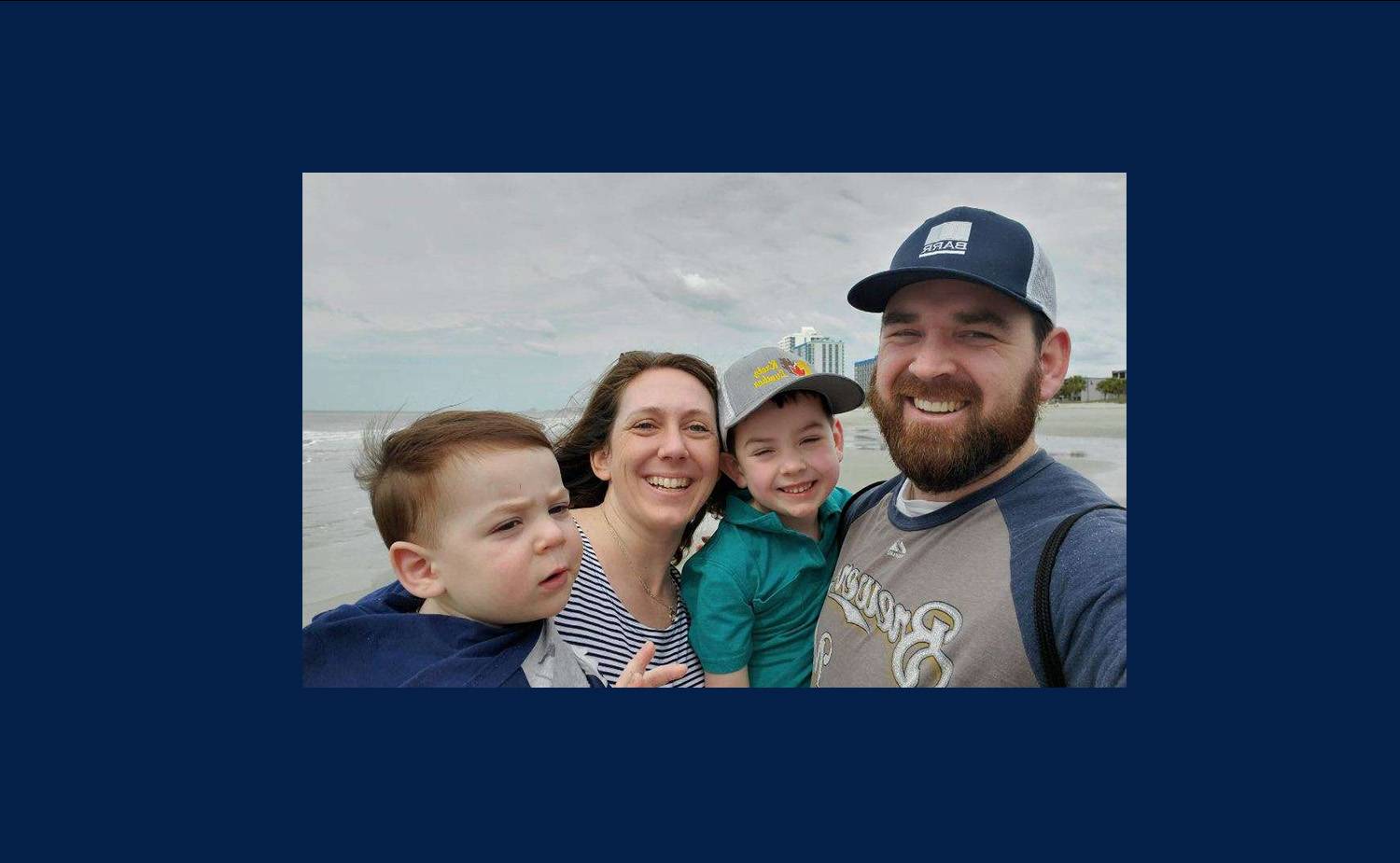 Pamela, her husband, and two young sons standing on a beach